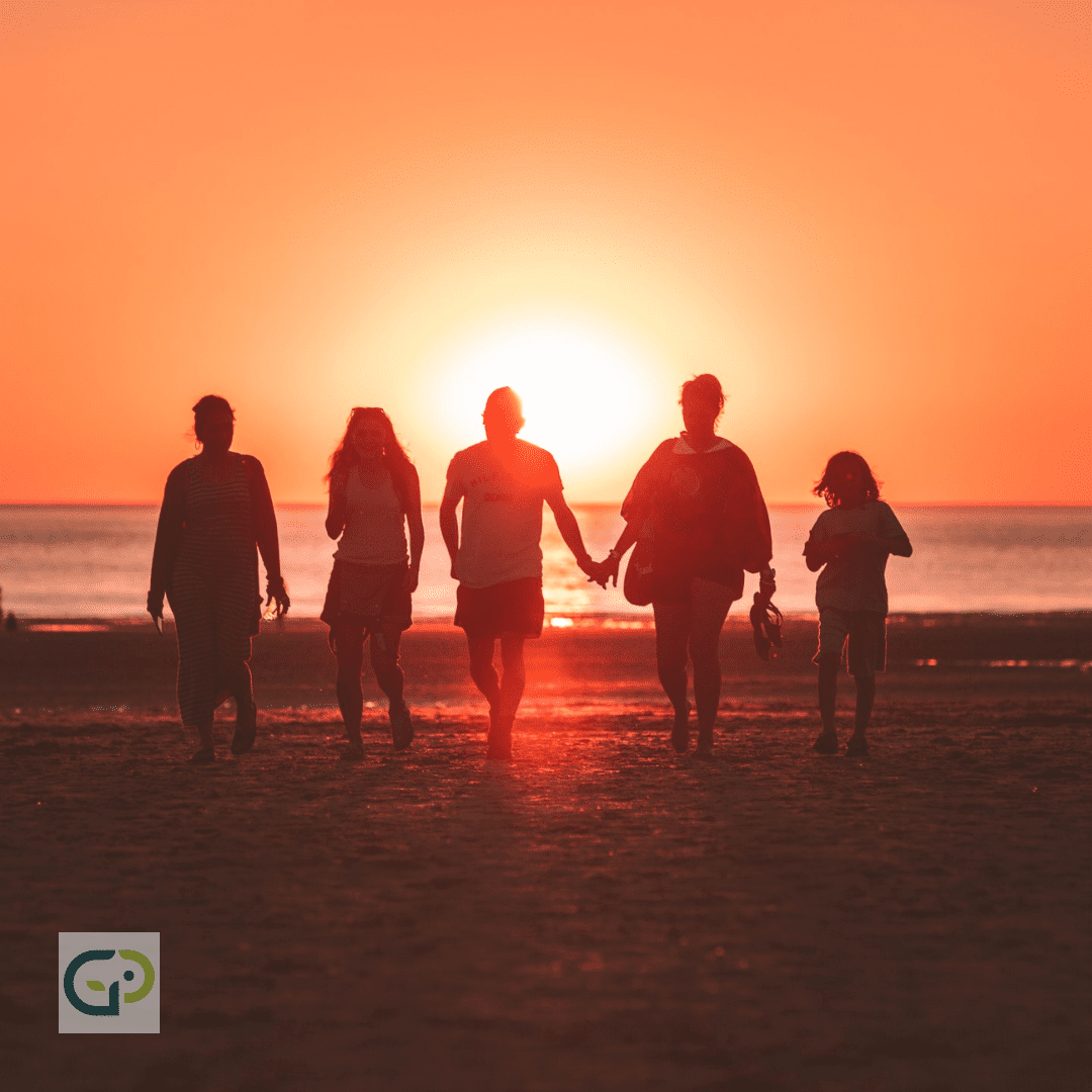 A family walking together on a beach at sunset