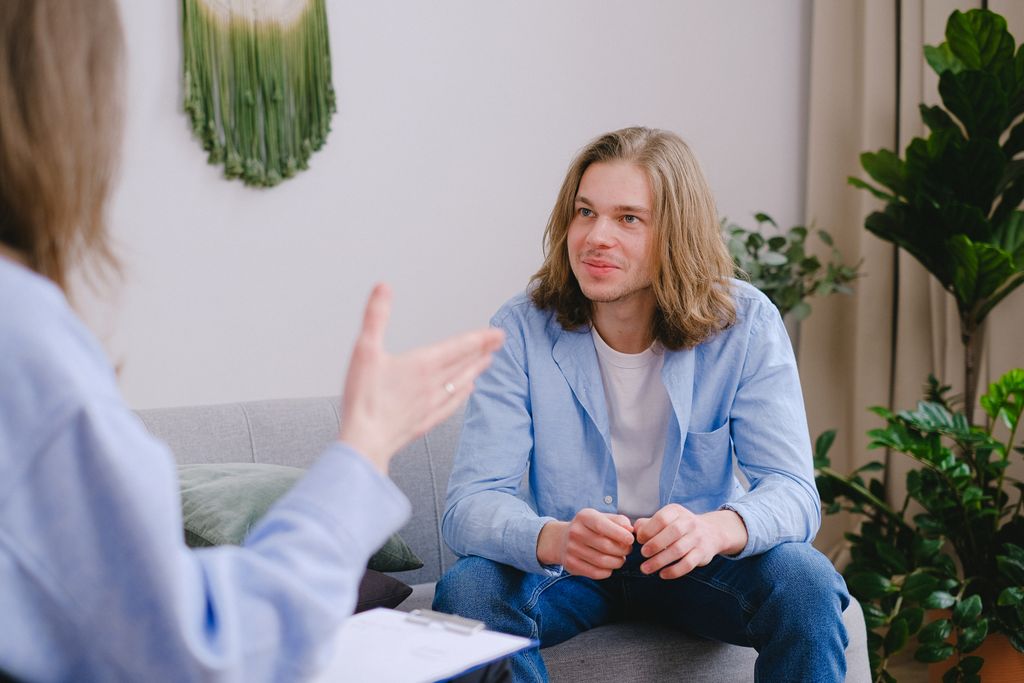 Young man with long hair in a therapy session, actively engaged in conversation.